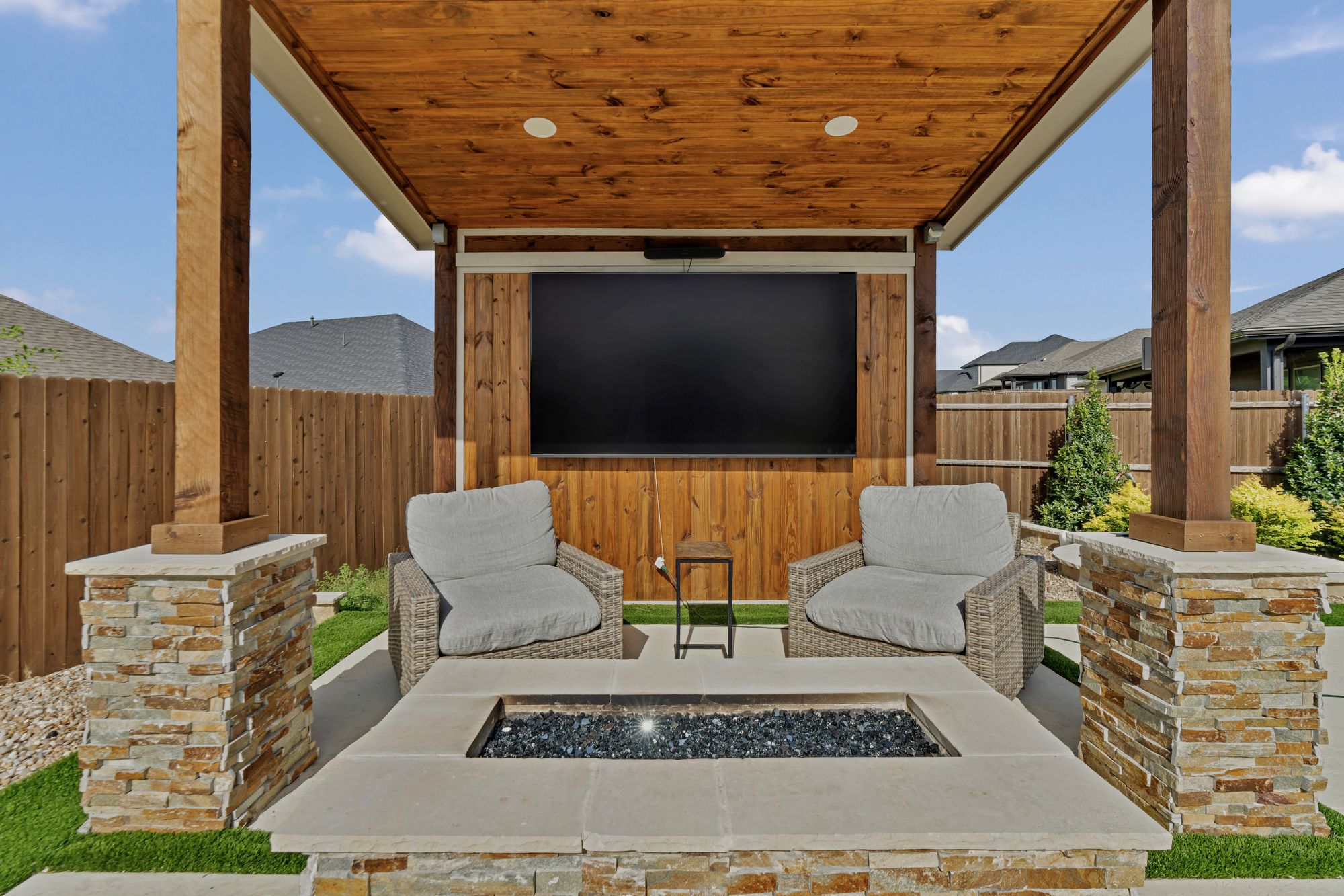 Cabana with a fireplace, TV and lounge chairs under a timber roof