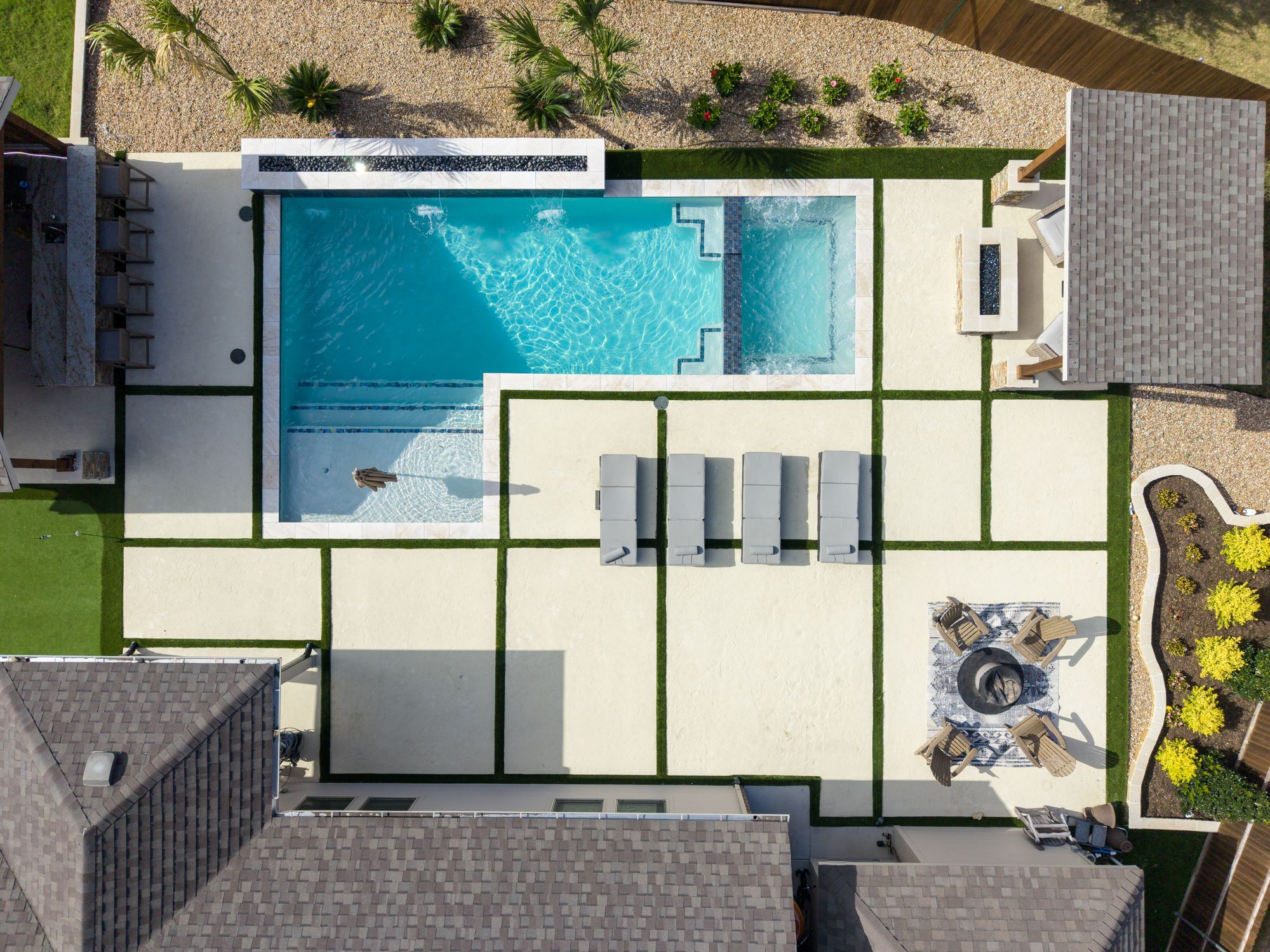 Drone view of concrete slabs and turf strips around a gunite pool