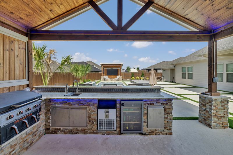 Outdoor kitchen under a timber pavilion looking out to the pool
