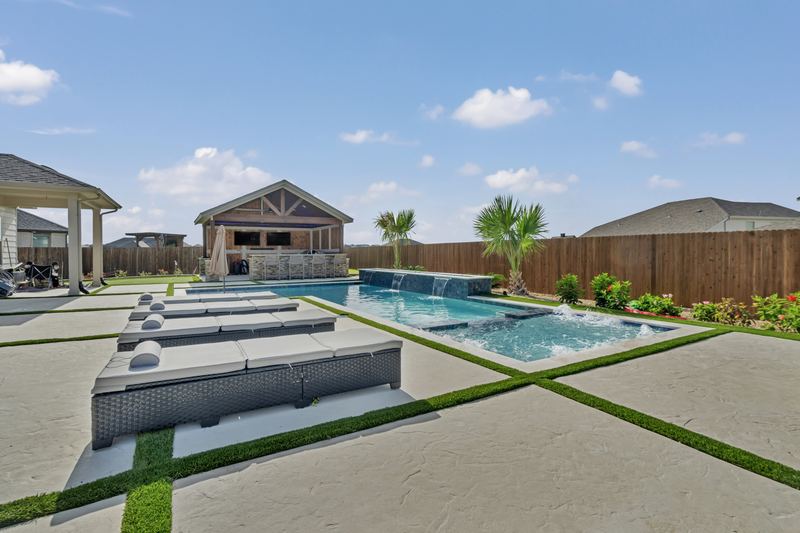 Loungers on slabs with turf strips beside a long pool