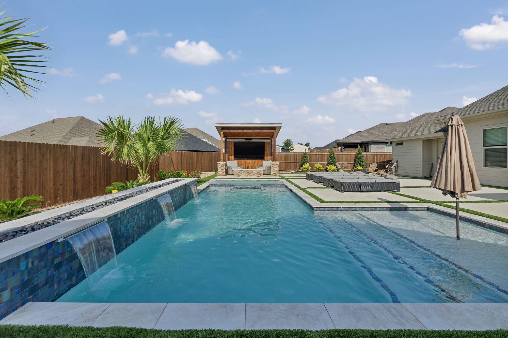 Raised glass tile wall with sheer descents and a cabana at the far end