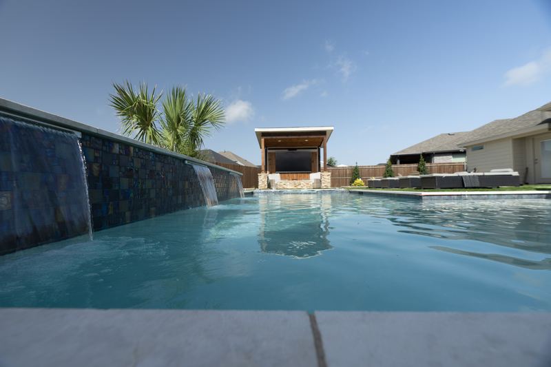 Sheer descents from a raised tile wall with a cabana beyond