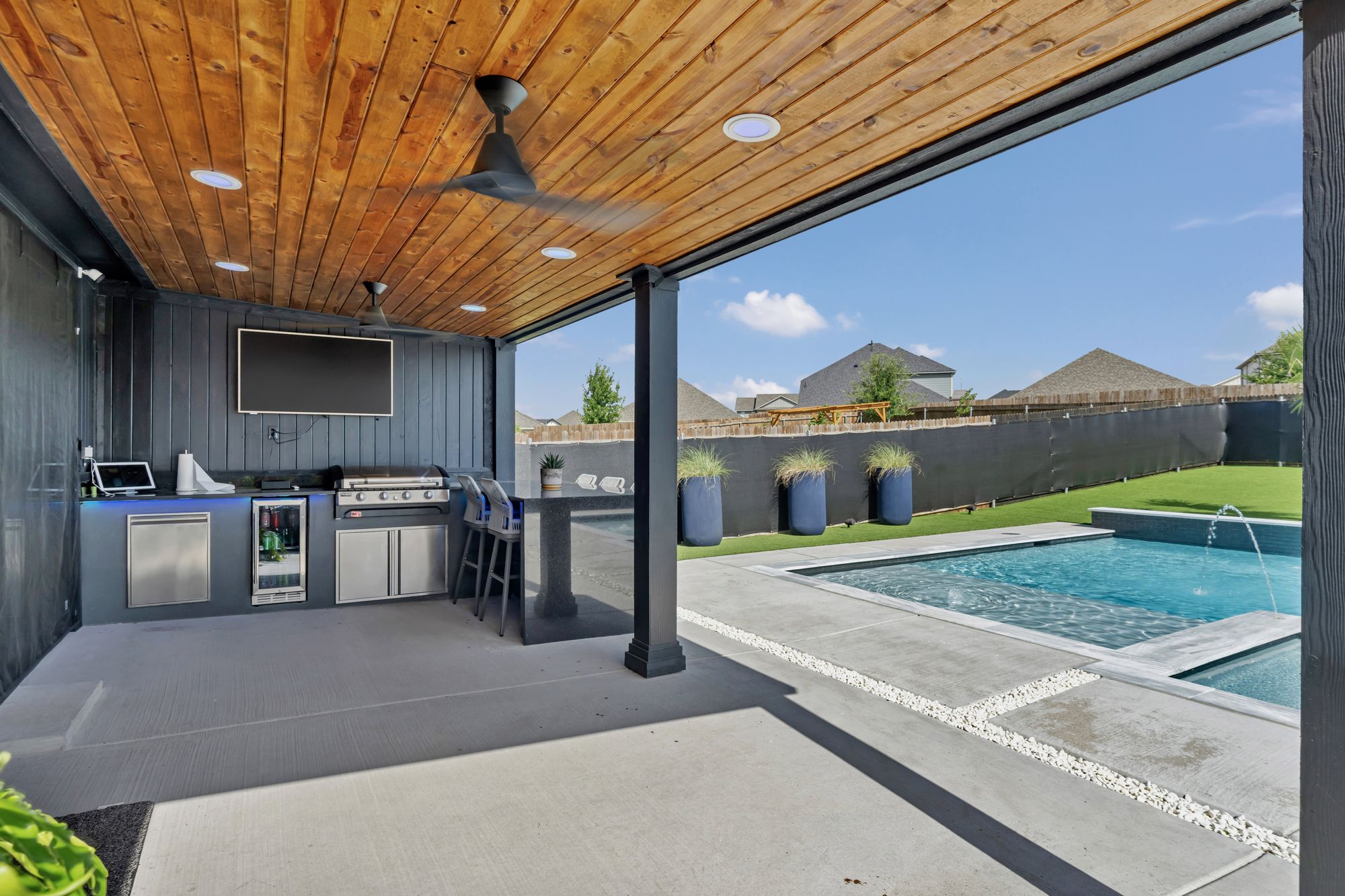 Covered patio kitchen with the pool beyond