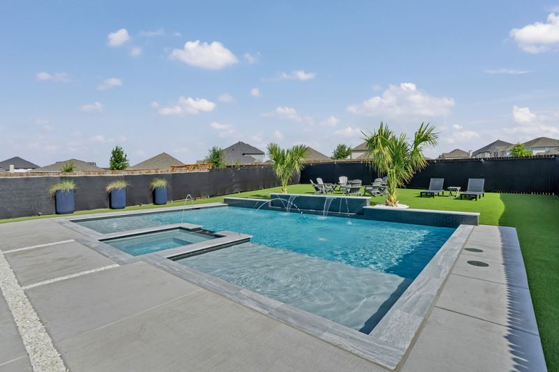 Square spa set inside a rectangular pool with a tanning ledge