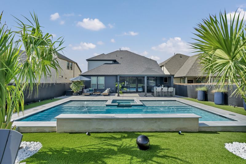Pool surrounded by turf with a raised concrete bench wall