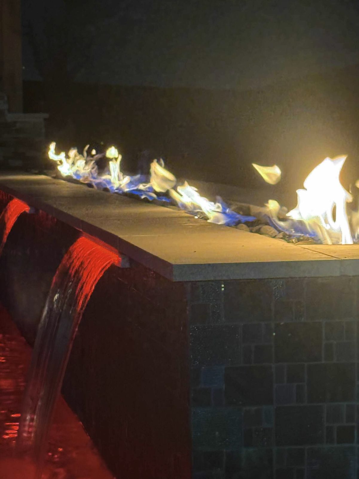 Gas fire line on a raised tile wall above red lit sheer descents at night