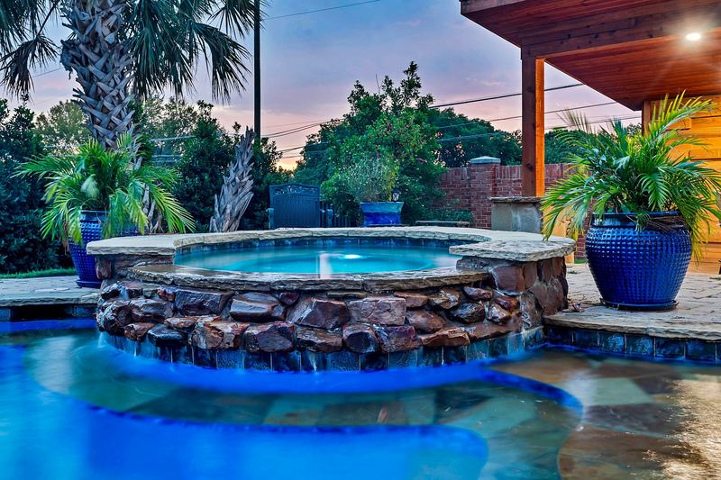 Lit spa spilling over a stone wall at dusk